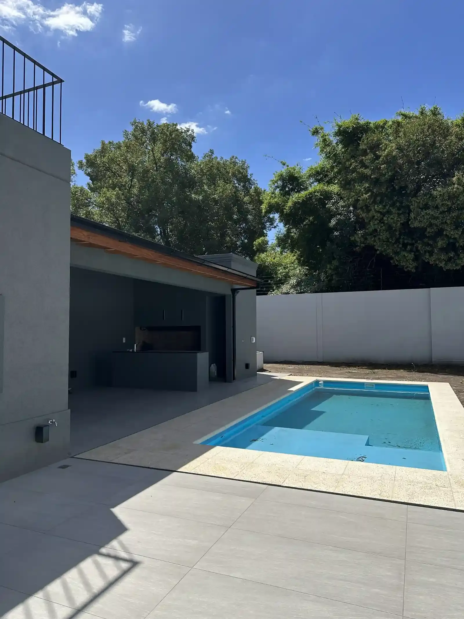 La parrilla bajo la galería, la pileta y el parque de Casa Adrogué