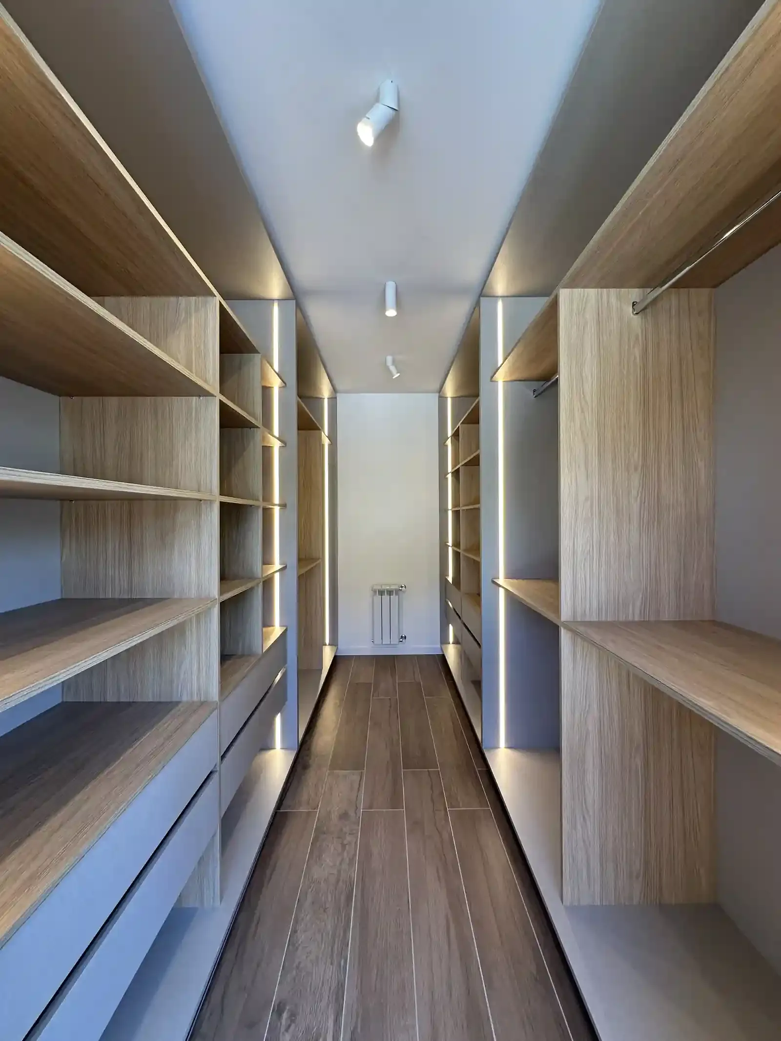 Vestidor de la suite principal de Casa Adrogué con equipamiento de madera a medida