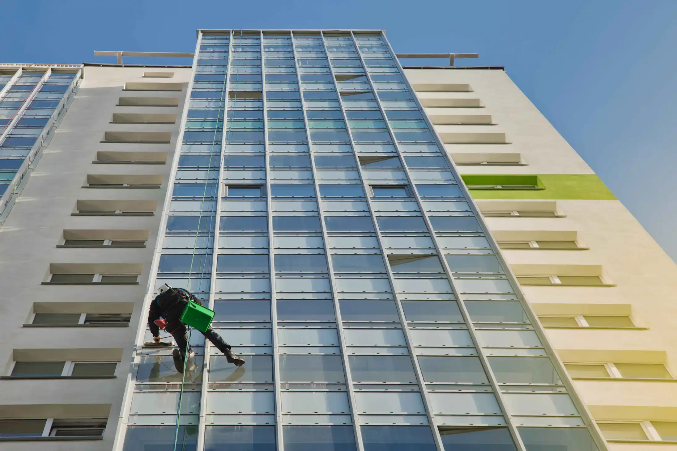 industrial-mountaineering-worker-hangs-residential-building-while-washing-exterior-facade-glazing-rope-access-laborer-hangs-wall-house-concept-urban-works-copy-space servicio de hidrolavado de grandes estructuras